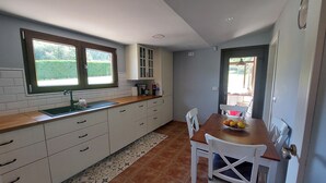 Une cuisine compacte comprenant un évier, des placards et un coin repas avec des chaises et une table.