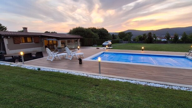 Une piscine avec une terrasse en bois, des sièges extérieurs et une vue sur les montagnes.
