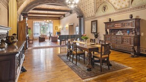 Un intérieur comprenant un coin repas, des meubles en bois, un lustre et des détails décoratifs au plafond.