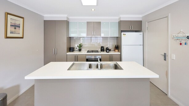 A modern kitchen with a central island, stainless steel appliances, and light-colored cabinetry. - Casa Laut; Sleeps 6, Walk to beach, Family Friendly, Pets welcome (Indented Head)