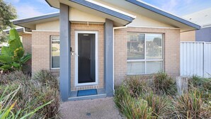 A modern two-story house with a flat roof, a front door with a glass panel, and a small front porch. - Casa Laut; Sleeps 6, Walk to beach, Family Friendly, Pets welcome (Indented Head)