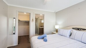 A bedroom with a bed, a bedside table with a lamp, a hanging towel, and a closet with a mirror. - Casa Laut; Sleeps 6, Walk to beach, Family Friendly, Pets welcome (Indented Head)