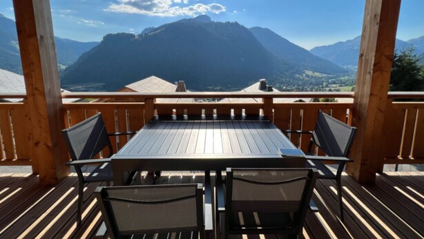 A wooden deck with a table and chairs, overlooking a mountainous landscape. - Apartment 'Petite Grange 202' with Mountain View, Private Terrace and Wi-Fi (Unknown)