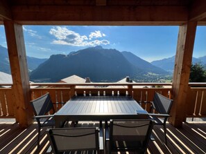 A wooden deck with a table and chairs, overlooking a mountainous landscape. - Apartment 'Petite Grange 202' with Mountain View, Private Terrace and Wi-Fi (Unknown)