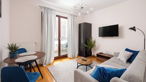 Una sala de estar moderna con un sofá, una mesa de centro, un televisor y un comedor con sillas y una mesa.