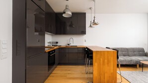 Une cuisine moderne avec des meubles de couleur sombre, un plan de travail en bois et un îlot central intégré, agrémenté de tabourets de bar.