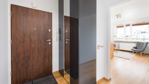 Un intérieur moderne avec une porte en bois, une porte coulissante noire et une vue sur le paysage urbain, visible à travers une grande fenêtre.