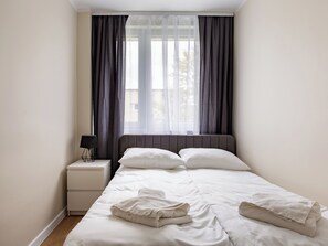 Relax in a serene bedroom with a large bed, bedside table, and sheer curtains.