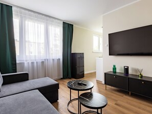 Relax in this stylish living room with a large flat-screen TV, comfortable sofa, and a small coffee table.