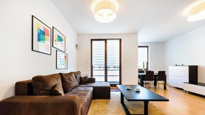 A modern living room with a brown leather sofa, a black coffee table, and a large window with blinds.