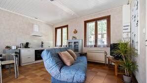 Un espacio habitable compacto con kitchenette, un sofá, una mesa de comedor y una planta en maceta.