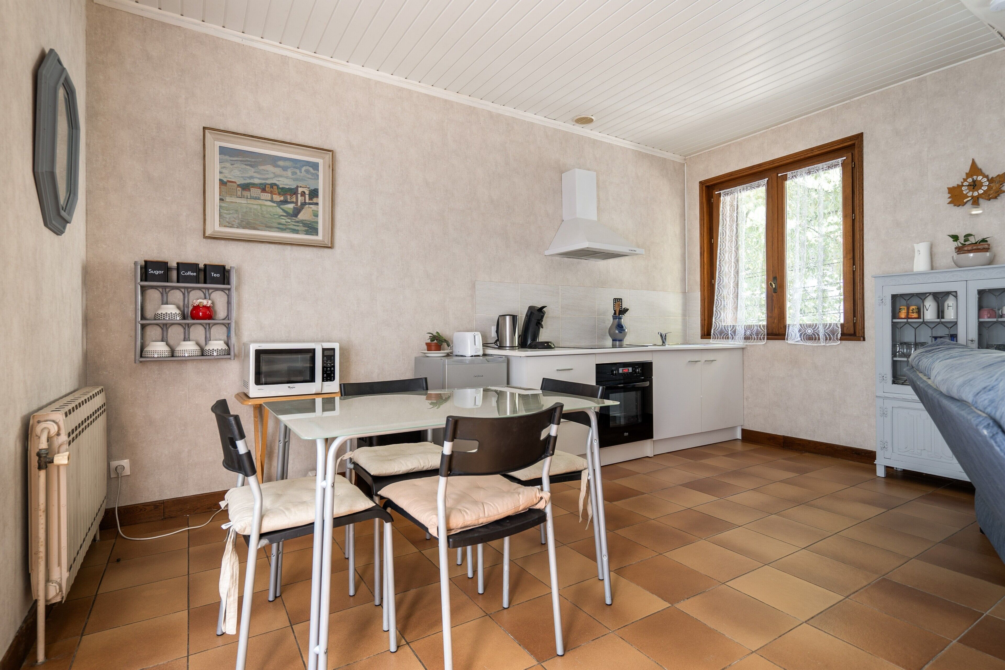 Une cuisine compacte comprenant une table à manger, des chaises, un four à micro-ondes et une cuisinière.