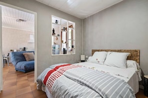 Ein Schlafzimmer mit Bett, Fenster, Kleiderschrank und einer kleinen Küchenzeile.
