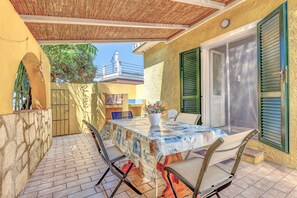 Un patio exterior con una mesa y sillas, un área cubierta y una vista de un edificio al fondo.