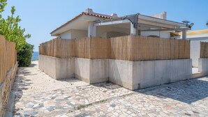 Un edificio con un patio empedrado, una valla de madera y vista al mar.
