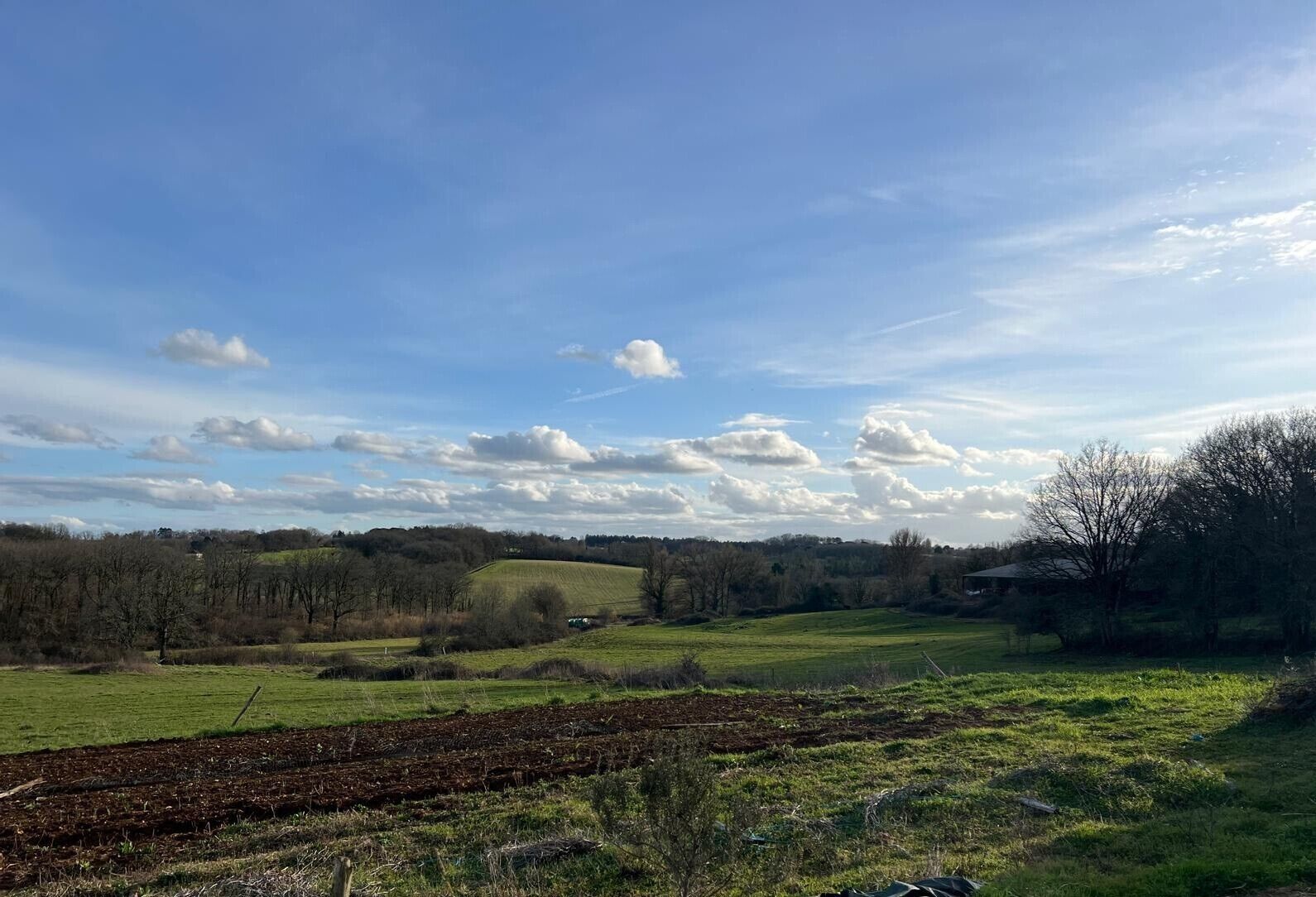 Paisaje rural con campos abiertos, cielo despejado y nubes dispersas.