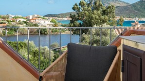 A balcony with a view of a lake, a chair, and a wooden deck. - Holiday Home 'Orizzonti 33' with Sea View, Private Terrace and Air Conditioning (Golfo Aranci)