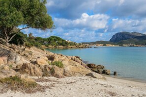 Paisaje costero con terreno rocoso, una playa de arena y una vista despejada del mar.