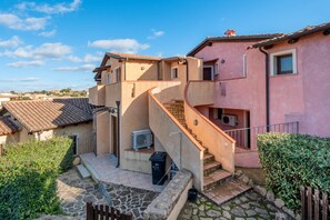 Un edificio residencial con un patio de piedra, una escalera y un pequeño jardín.