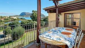 Un balcon avec une table et des chaises, offrant une vue panoramique sur un lac et des montagnes.
