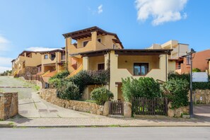 Un immeuble résidentiel doté de nombreux balcons, d’un mur en pierre et d’une entrée pavée.
