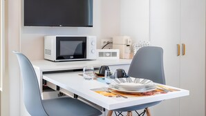 A compact kitchenette with a microwave, toaster, and coffee maker, a dining area with a table and chairs, and a flat-screen TV mounted above the counter. - Apartment 'Liolà' with Mountain View, Wi-Fi and Air Conditioning (Scicli)
