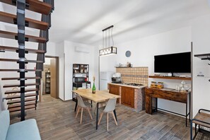 Une cuisine moderne avec un coin repas, un escalier et un téléviseur.