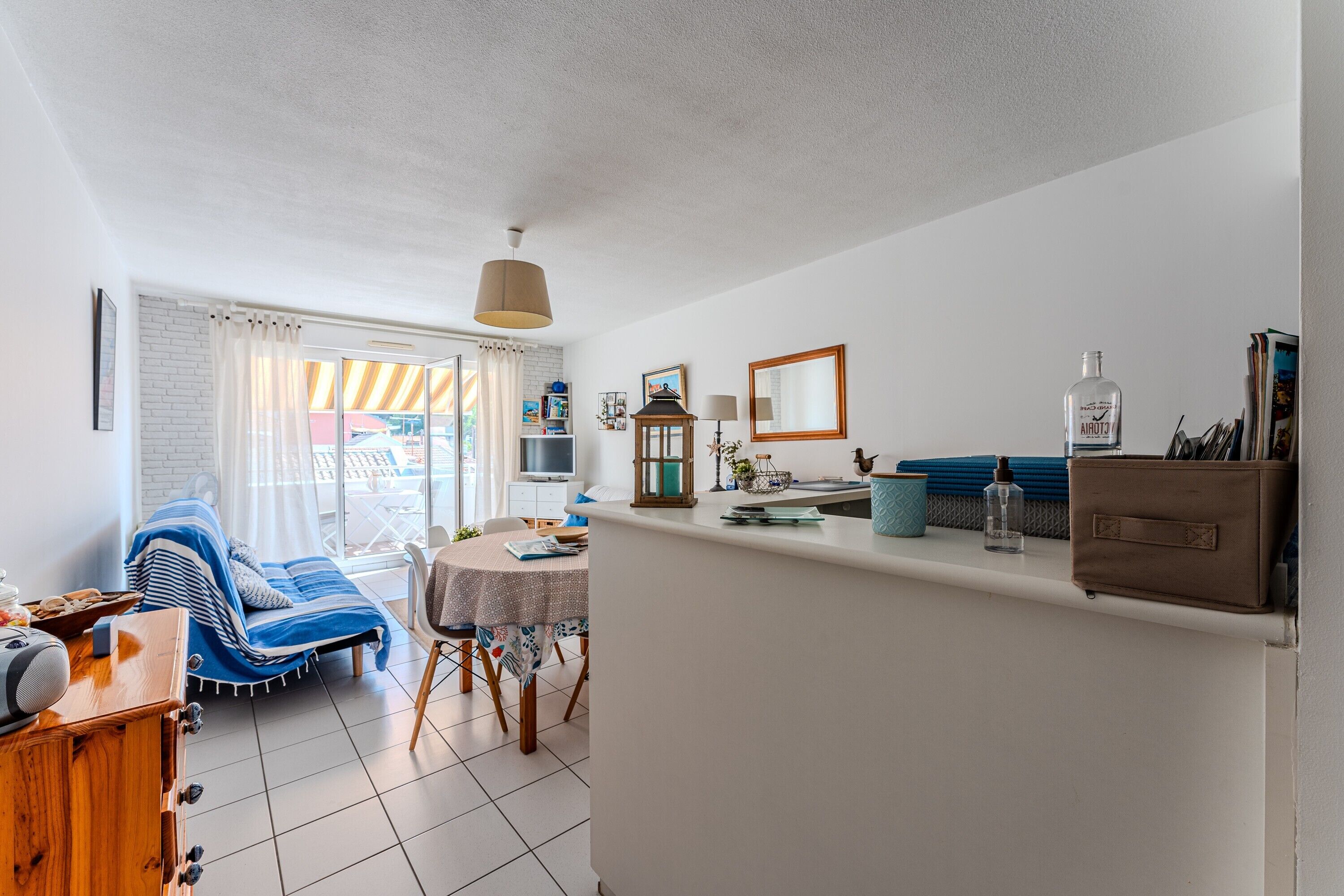 Ein modernes Wohnzimmer mit Sofa, Esstisch und Küchenzeile mit Arbeitsfläche und Schränken.