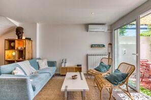 A modern living room with a sofa, wicker chairs, a coffee table, and a bookshelf.