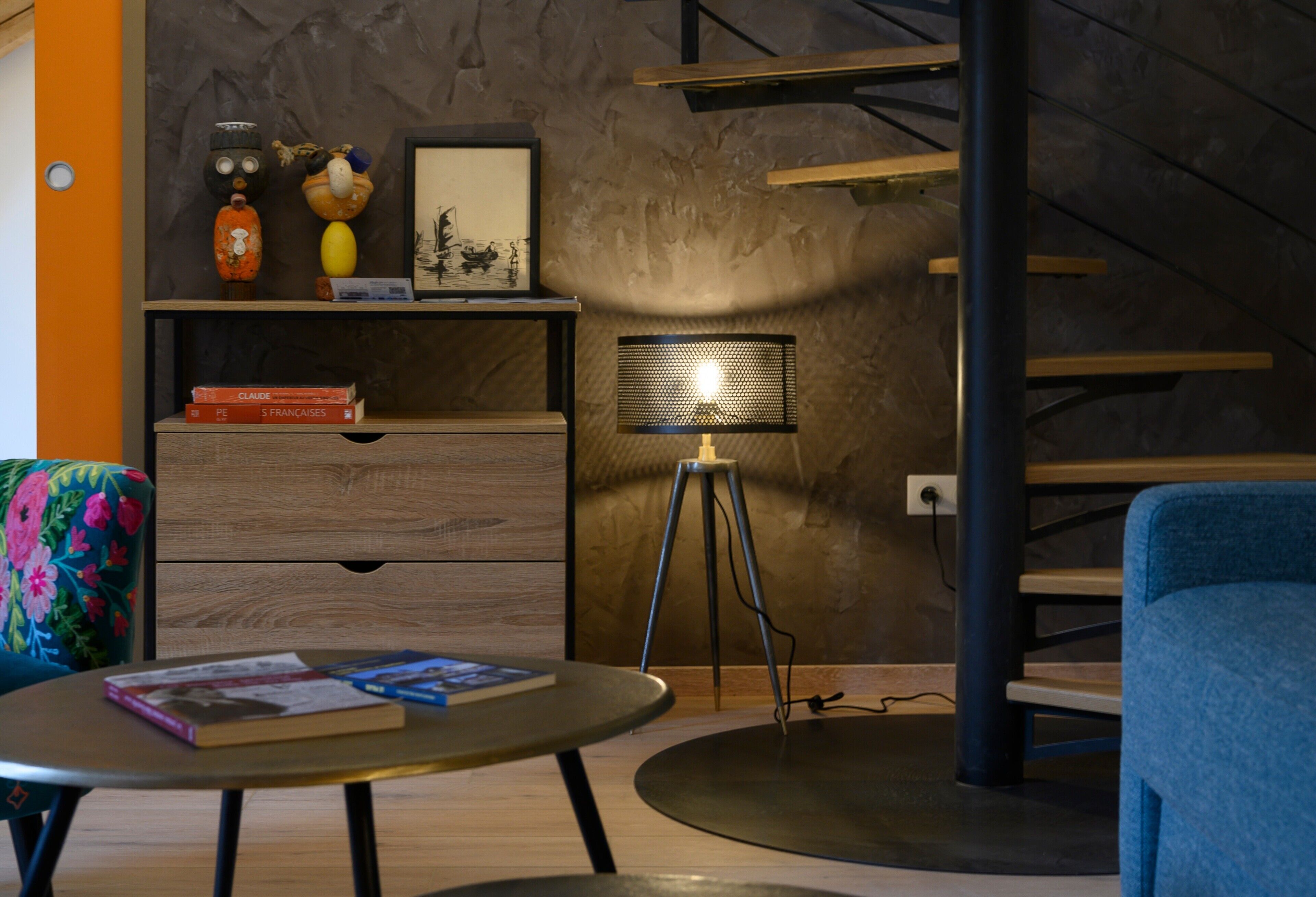 A modern living room with a sofa, two coffee tables, a bookshelf, a lamp, and a staircase.