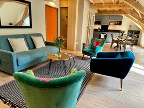 Un salon moderne comprenant un canapé, des fauteuils, une table basse et un coin repas avec des chaises et une table.