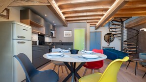A modern kitchen with a built-in refrigerator, a dining table with chairs, and a spiral staircase. - Apartment 'Seigneurie Fouquet - Tousquet' with Wi-Fi (Le Palais)