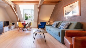 A loft-style room with a dining area, a sofa, and a window with a view.