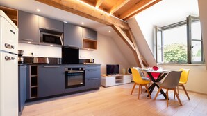A modern kitchen with grey cabinets, a microwave, and a dining area with yellow chairs.