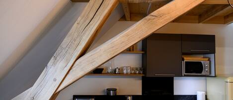 Una cocina con vigas de madera, microondas y cafetera.
