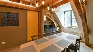 A dining area with a long table, chairs, and hanging light fixtures.