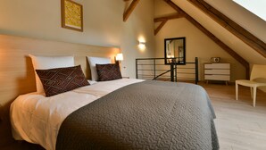 A bedroom with a bed, a nightstand, a lamp, a mirror, a dresser, and a chair.