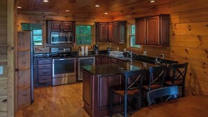 A wooden cabin interior with a kitchen featuring a stove, microwave, and cabinets. - Lakefront Mountain Retreat on Watauga Lake (Butler)