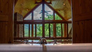 A bathroom with a wooden ceiling, a large window, and a bathtub. - Lakefront Mountain Retreat on Watauga Lake (Butler)