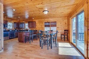 A spacious wooden cabin with a kitchen, dining area, and large windows.