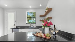 A modern kitchen with a central island, a window with a view of greenery, and a built-in wine rack.