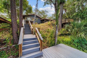 Una escalera de madera que conduce a una casa moderna rodeada de árboles.
