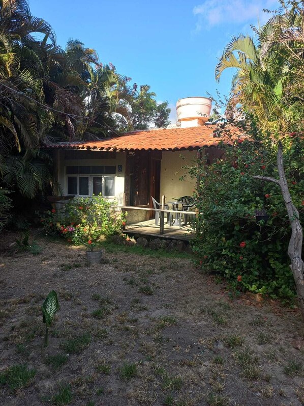 Una casa con techo de tejas, un tanque de agua visible y un patio con mobiliario exterior.