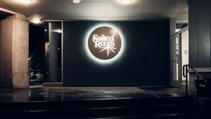 Ein Gebäudeeingang mit einem Schild, auf dem 'Salted Roots' steht.