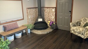 A cozy living room with a fireplace, a bench, a door, and a floral-patterned armchair. - 2-bedroom House in beautiful Grand Island,NY! 4 miles from Niagara Falls! (Grand island)