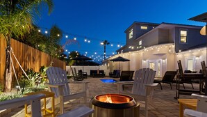 Un espace extérieur aménagé en terrasse, avec des fauteuils Adirondack, un foyer et des guirlandes lumineuses.