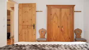 A bedroom with a bed, two wooden chairs, and a wardrobe with a decorative key. - La Siala Apt.54 by Interhome (Falera)