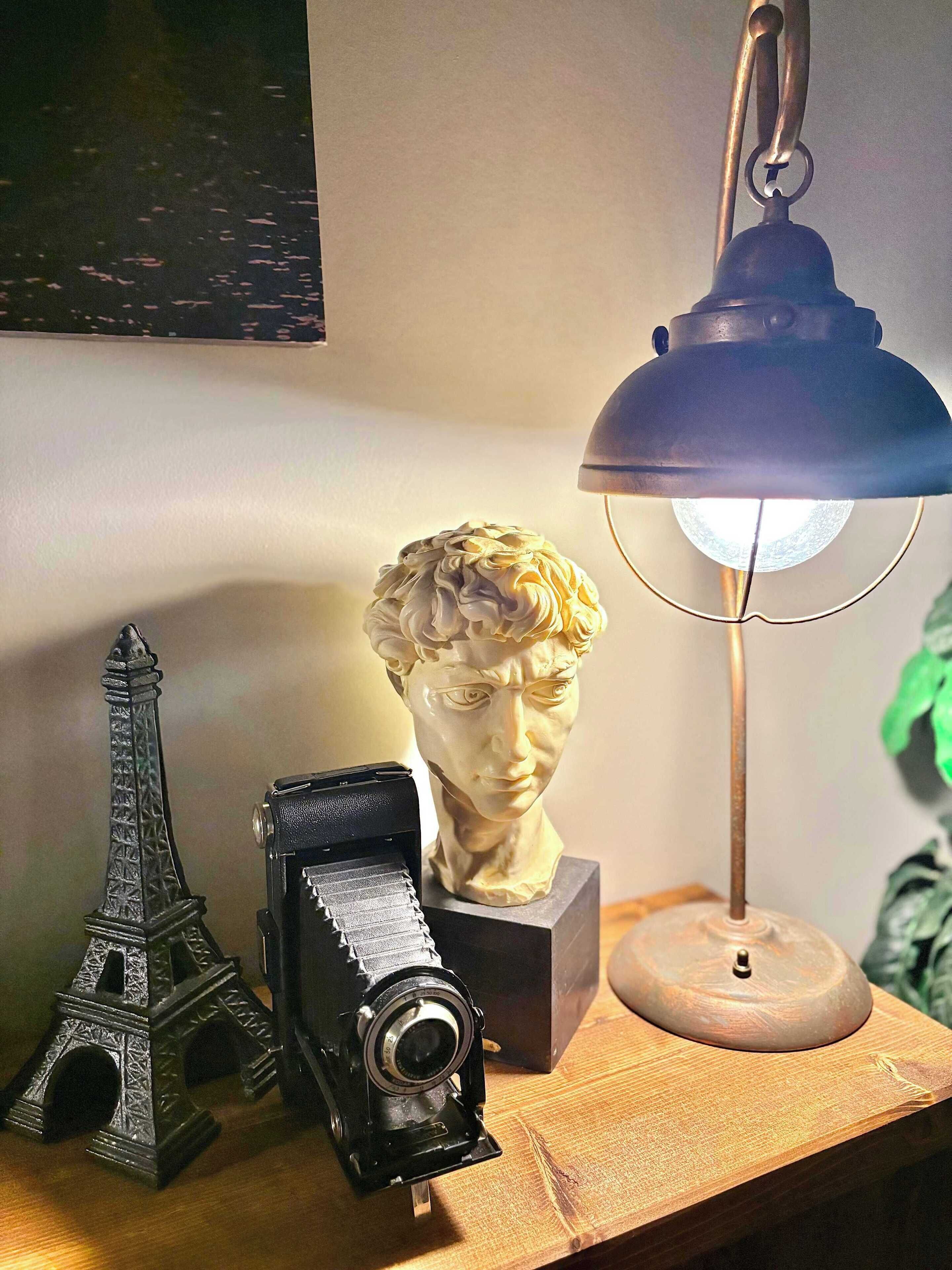 Un bureau avec un appareil photo, un buste sculpté et une maquette de la tour Eiffel.