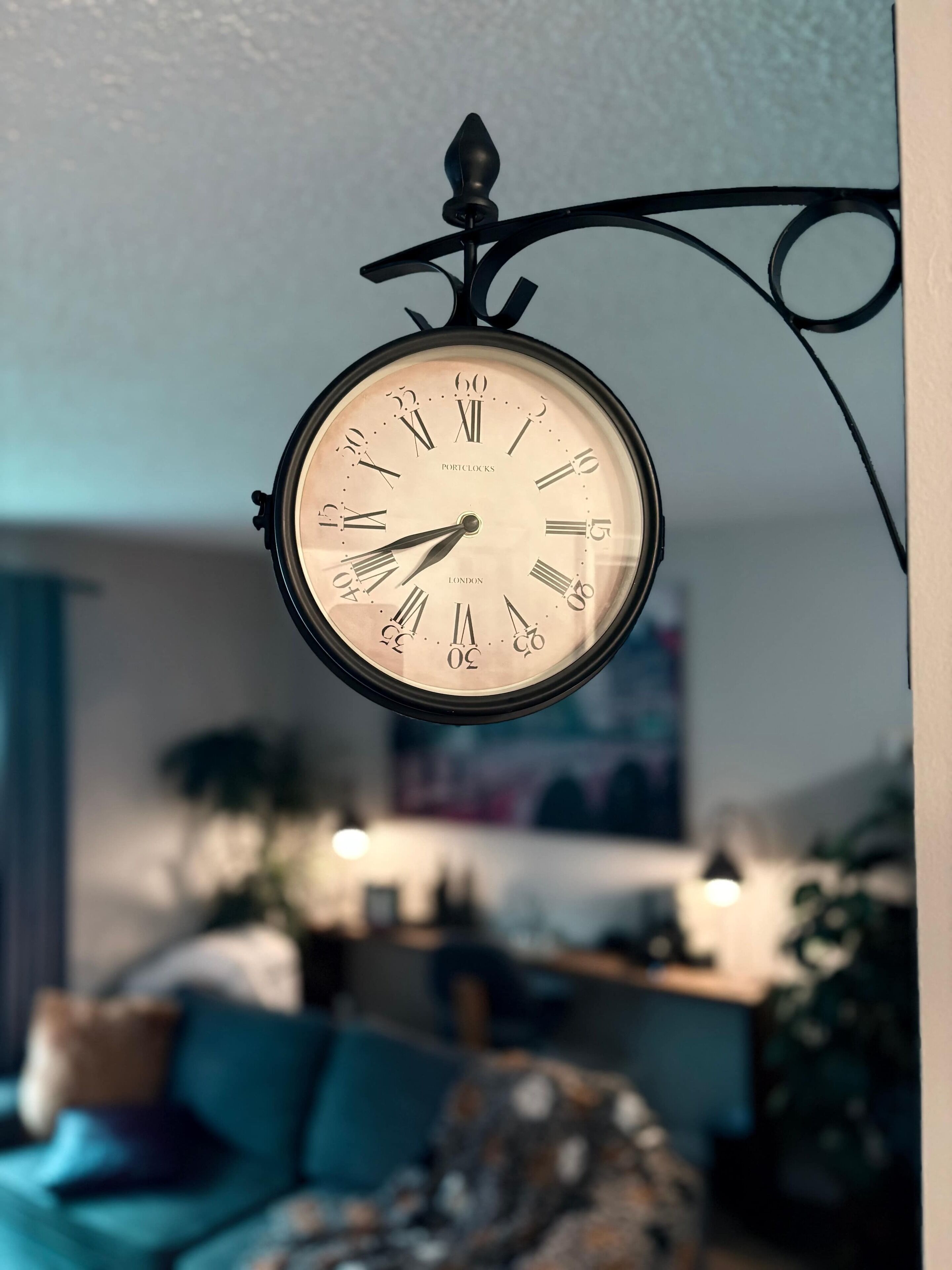 A wall-mounted clock with Roman numerals and the words "PORTCOCKS" and "LONDON" on its face.
