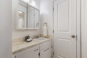 Une salle de bain avec un lavabo blanc, un miroir et une porte.